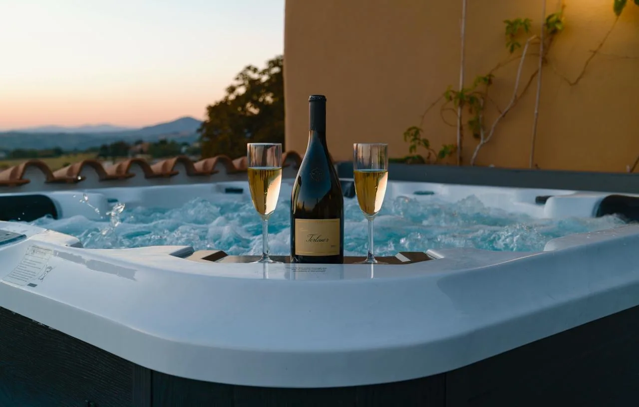 Vasca idromassaggio sul terrazzo al tramonto, con vino e calici